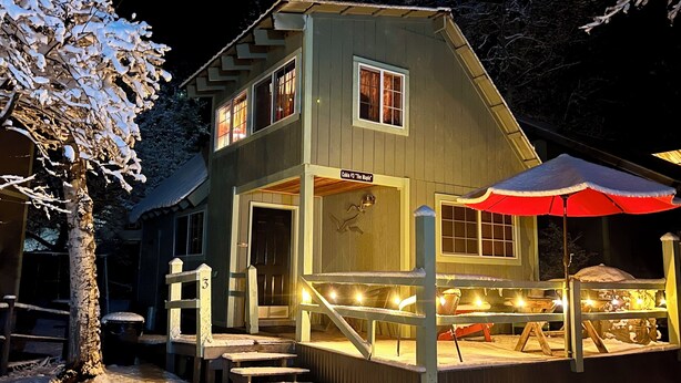 Eine zweistöckige Hütte mit überdachter Veranda und Treppen zum Eingang.