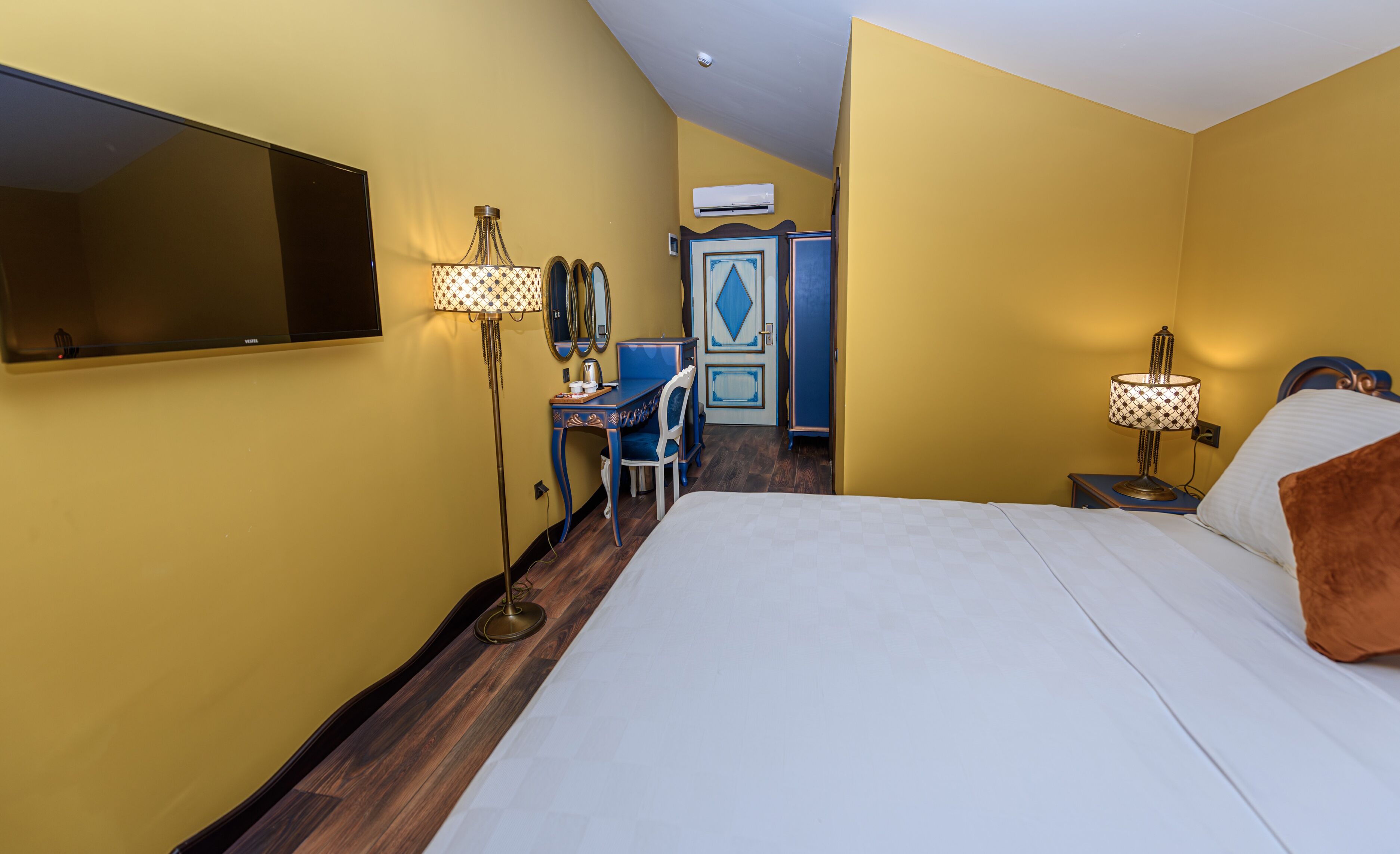 Una habitación de hotel con cama, escritorio, silla, espejo y armario.