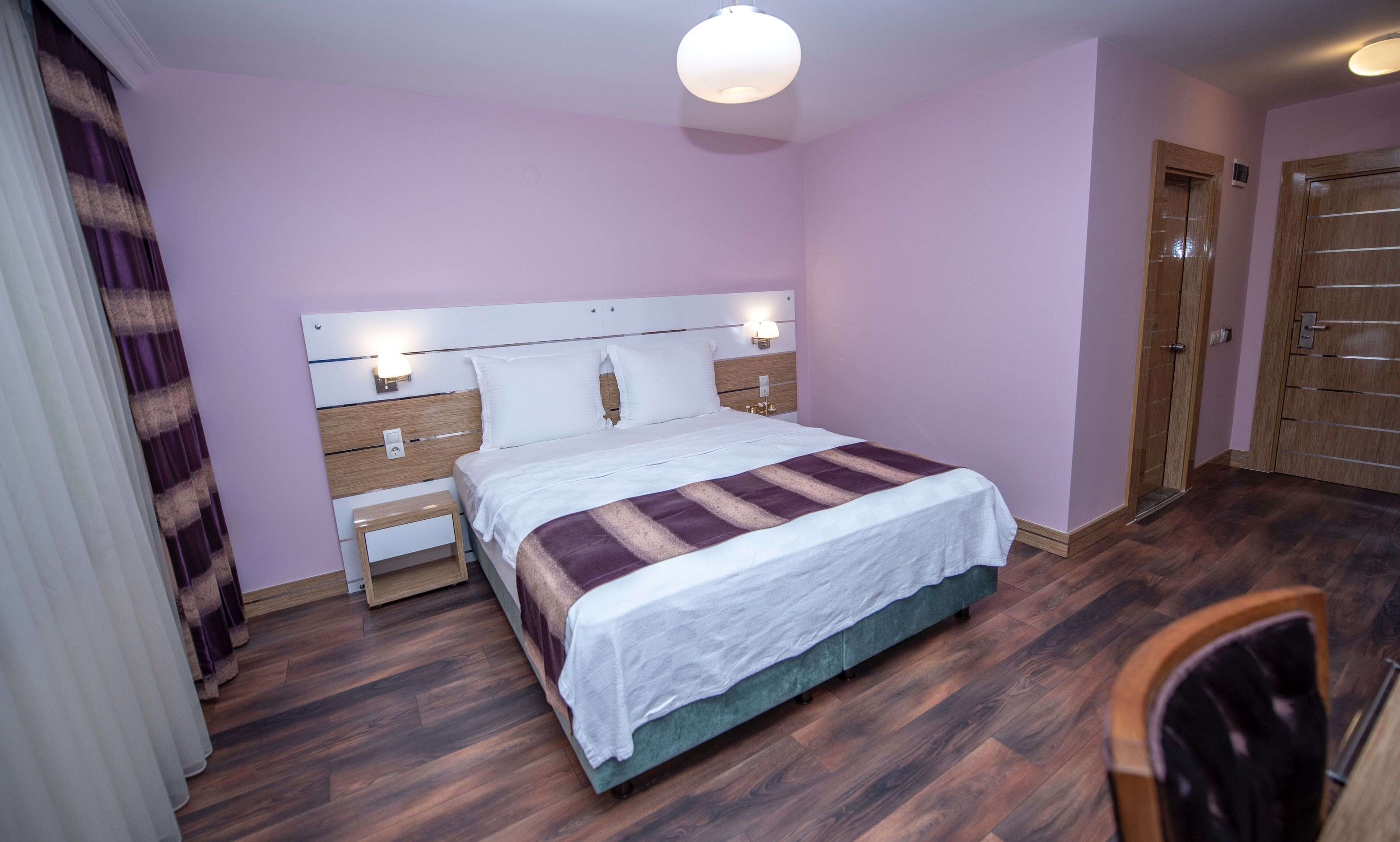A neatly arranged bedroom with a bed, bedside tables, and a wardrobe.