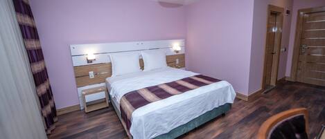 A neatly arranged bedroom with a bed, bedside tables, and a wardrobe.
