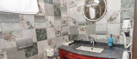 A bathroom with a toilet, sink, and mirror.