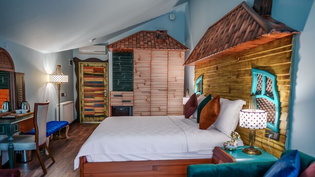 A bedroom with a wooden bed, a small desk, a chair, and a sofa. - TOK EPİK HOTEL (Bursa)