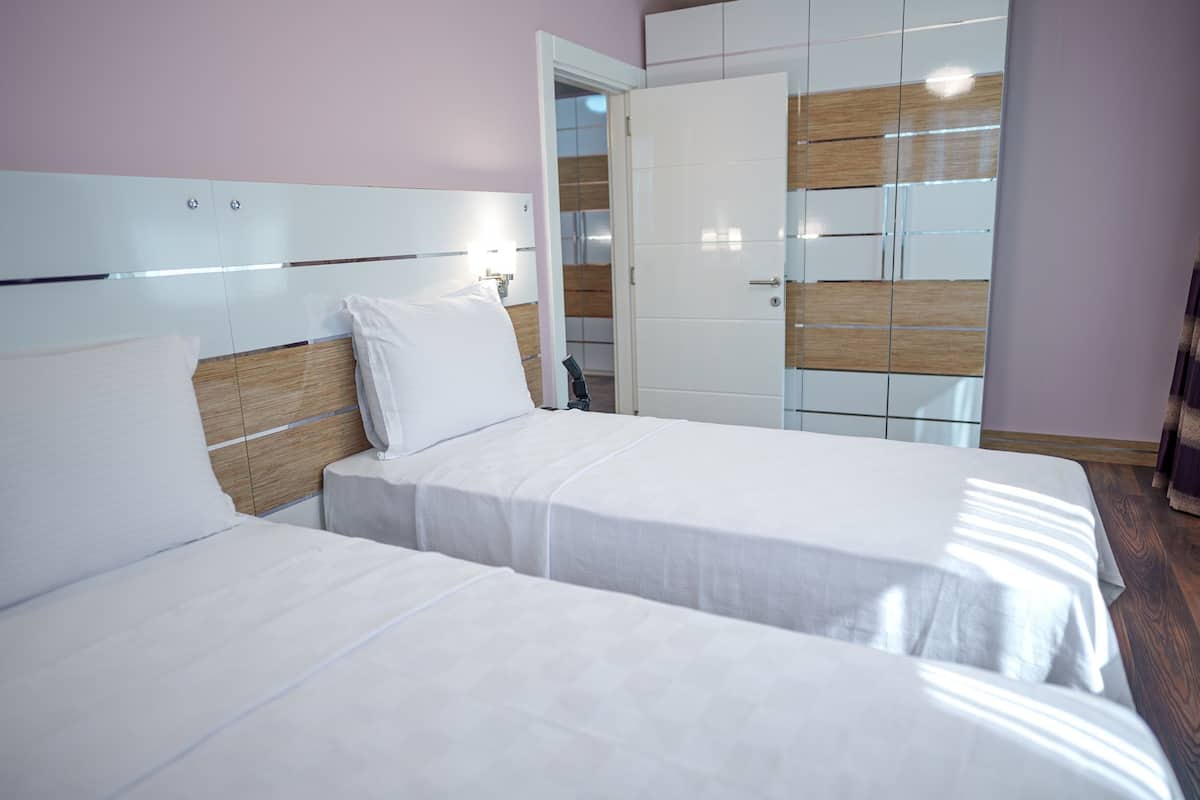 Habitación de hotel con dos camas, un armario y un espejo.