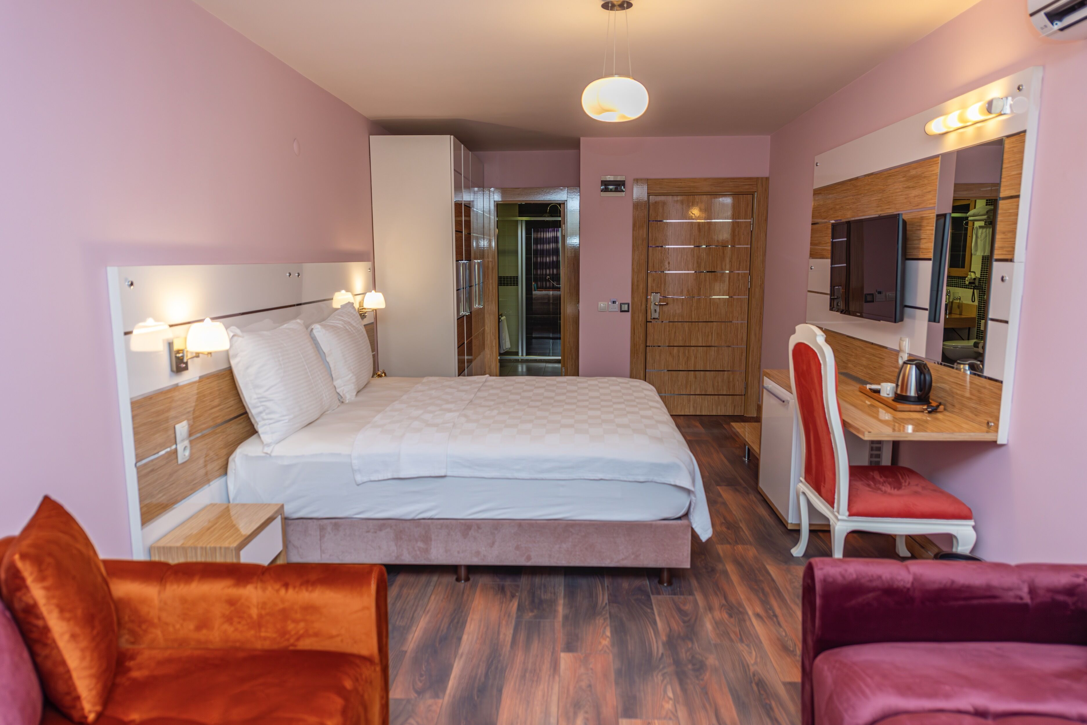 A hotel room with a bed, a desk with a chair, a TV, and a mirror.