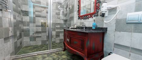 A bathroom with a glass shower enclosure, a vanity with a red cabinet, and a toilet.