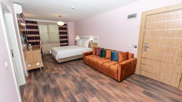 A hotel room with a bed, a sofa, a wooden wardrobe, and a desk with a chair.