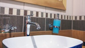 A bathroom with a blue glass sink, a chrome faucet, and a mirror above. - TOK EPİK HOTEL (Bursa)