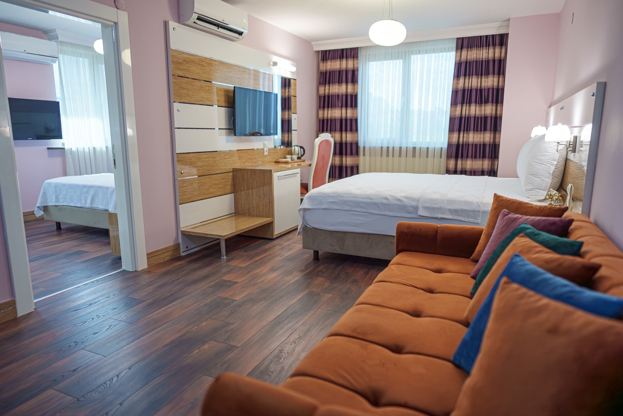 Una camera d'albergo con un letto, un divano, una scrivania e una televisione.