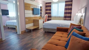Una habitación de hotel con cama, sofá, escritorio y televisión.
