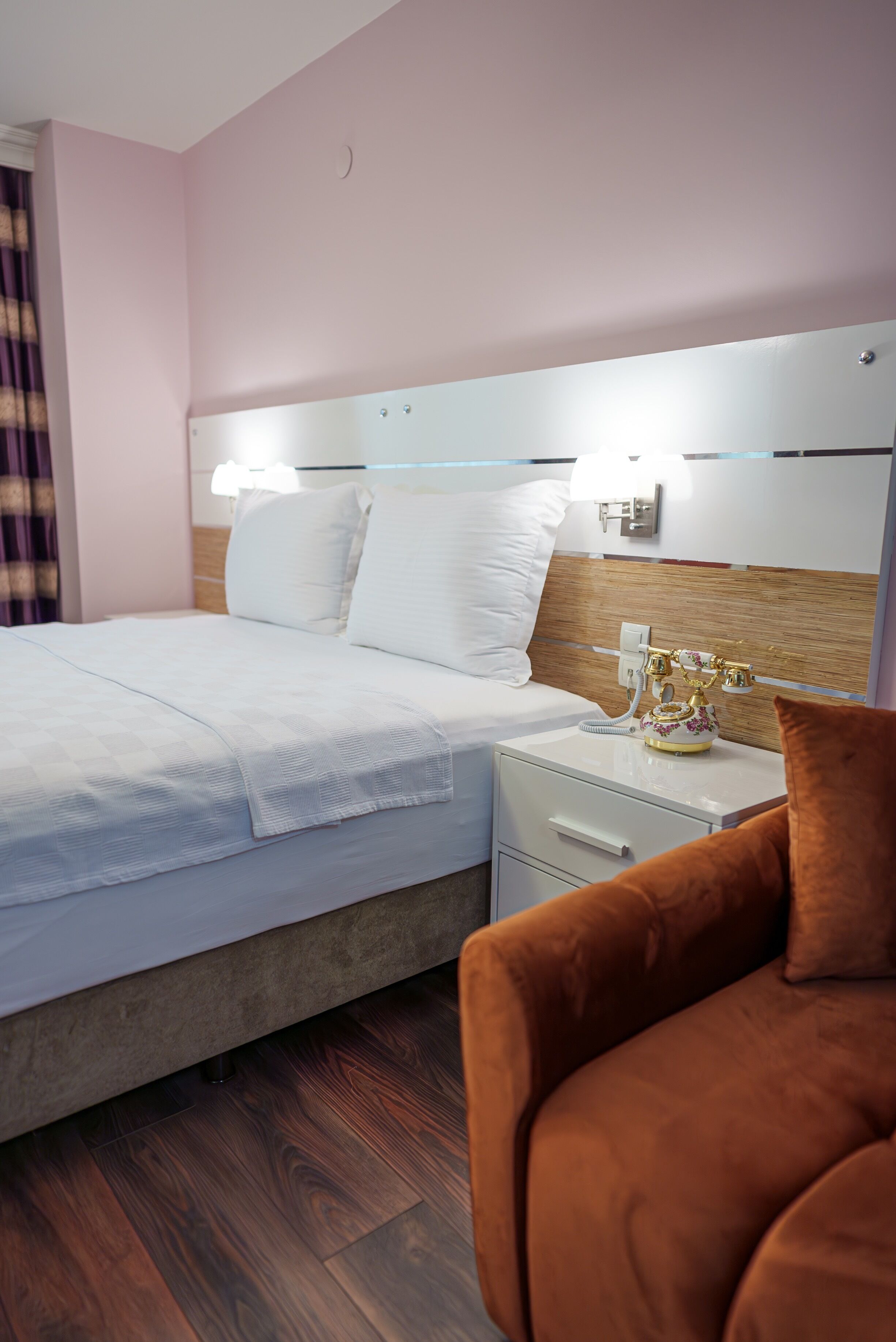 A neatly made bed with white linens, a wooden headboard, and a bedside table with a lamp and a decorative item.