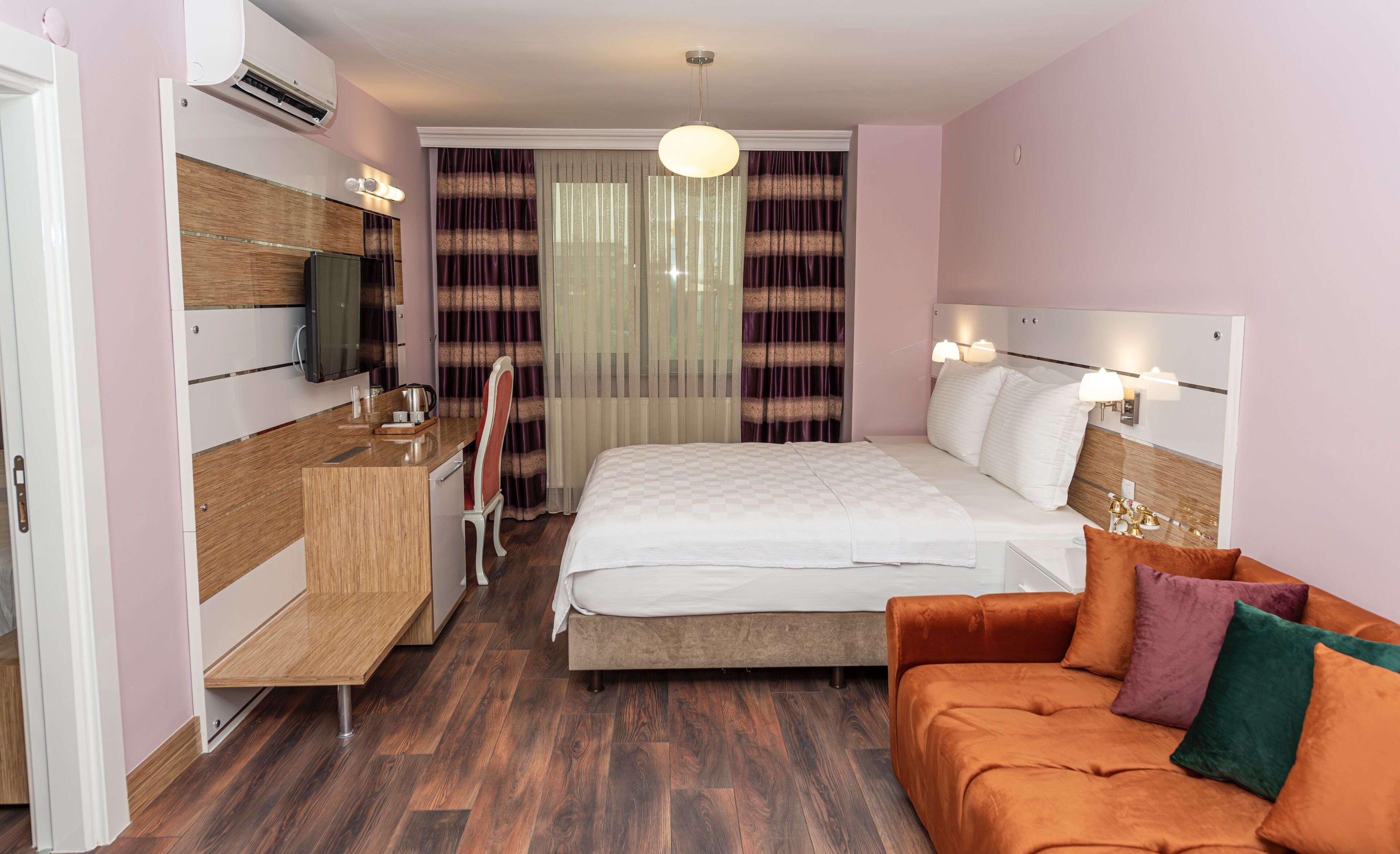 A hotel room with a bed, a sofa, a desk, and a television.