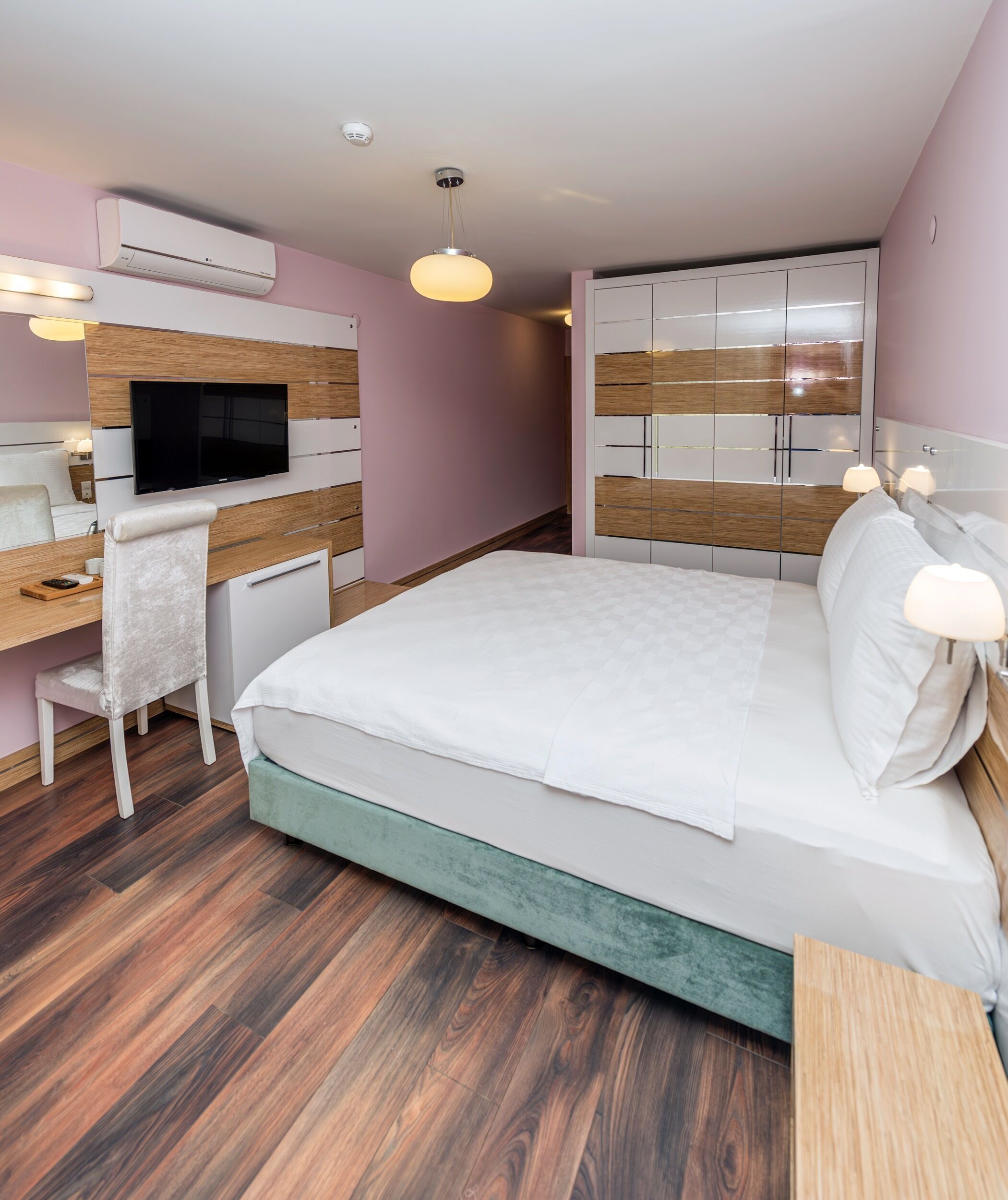 Un dormitorio moderno con cama, mesitas de noche, un escritorio, un televisor y un armario.