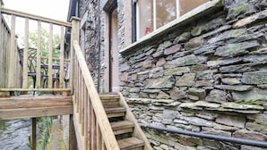 A stone staircase leading to a wooden deck with a railing, overlooking a body of water. - Riverbank (Ambleside)