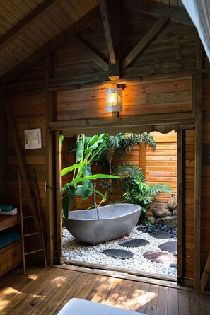 Ein Holzblockhaus-Interieur mit einem Steinhaufen, Pflanzen und einer Himmelsleiter.