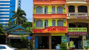 A multi-story hotel with balconies, a sign for a cafe, and a visible entrance. - Quang Vinh 2 Hotel (Bac Nha Trang)