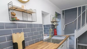 A modern kitchen with a wooden countertop, a sink, and a built-in storage unit. - Bay Cottage Morecambe Beach 4 Berth 2 Bedrooms (Morecambe)