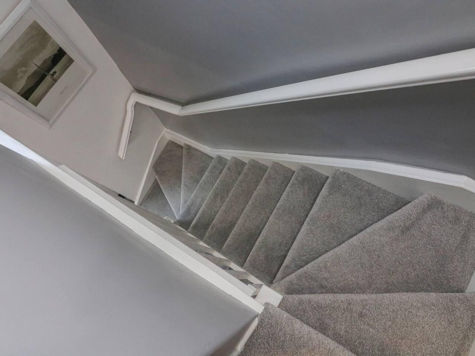 A staircase with grey carpeted steps and white walls.