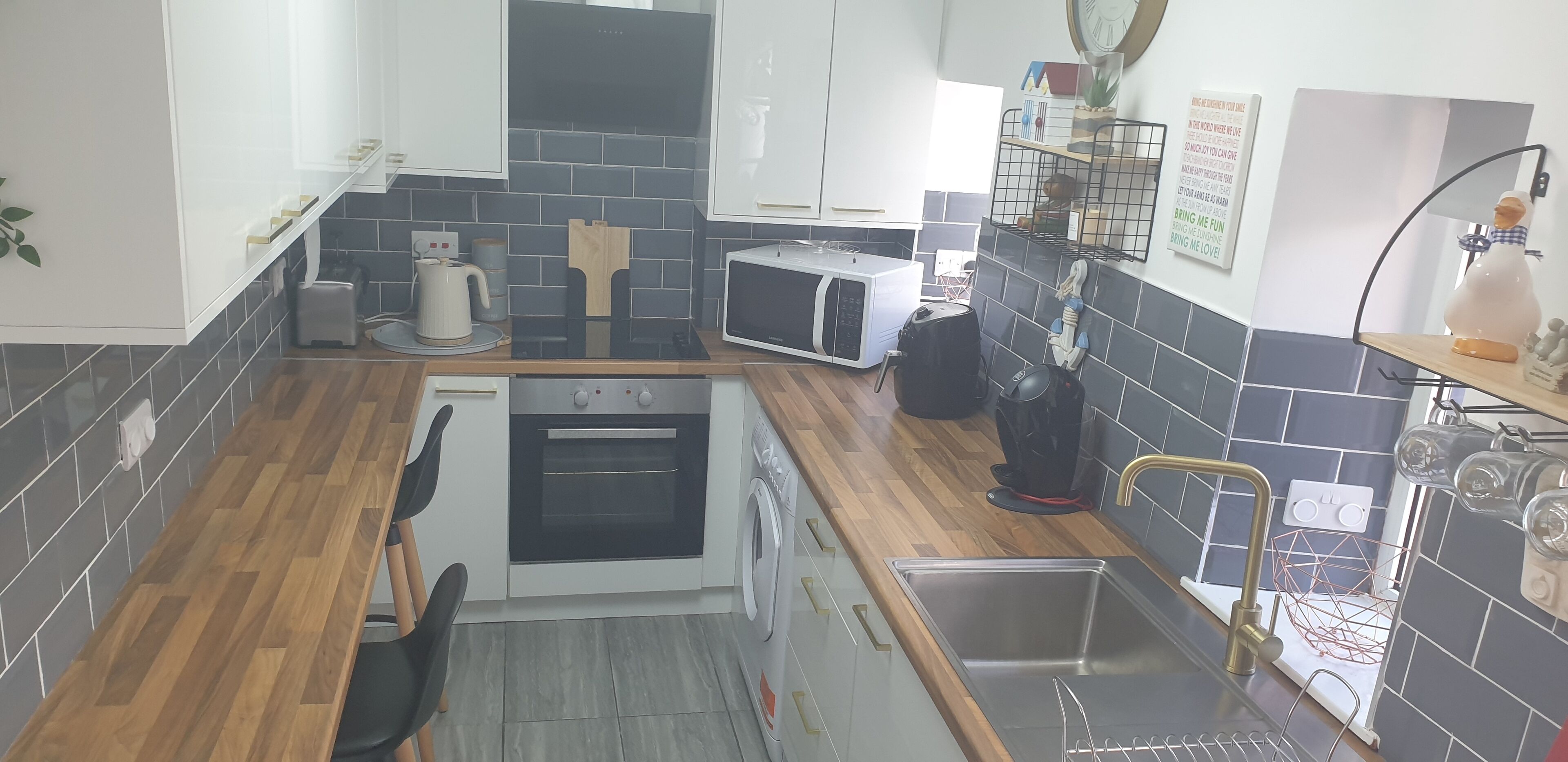 Een kleine keuken met een magnetron, oven en spoelbak.