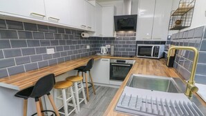 A compact kitchen with a wooden countertop, a built-in oven, a microwave, and a sink with a gold faucet. - Bay Cottage Morecambe Beach 4 Berth 2 Bedrooms (Morecambe)