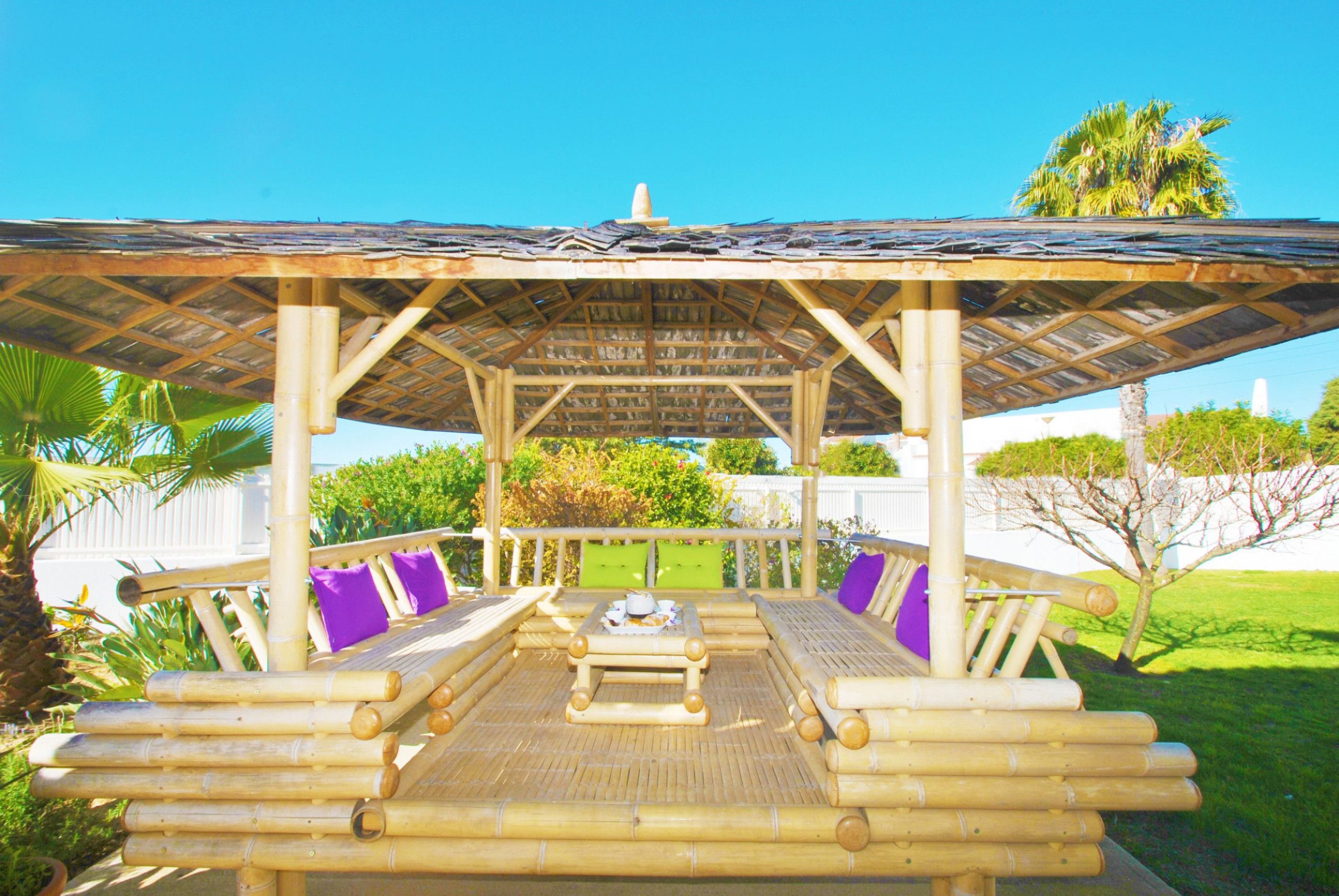 A covered outdoor seating area with bamboo furniture and cushions.