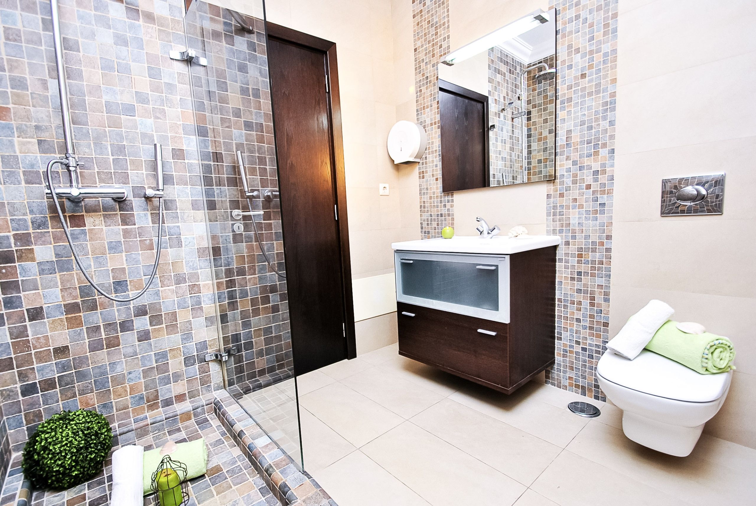 Un baño moderno con ducha acristalada, tocador con espejo y retrete.