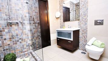 Un baño moderno con ducha acristalada, tocador con espejo y retrete.