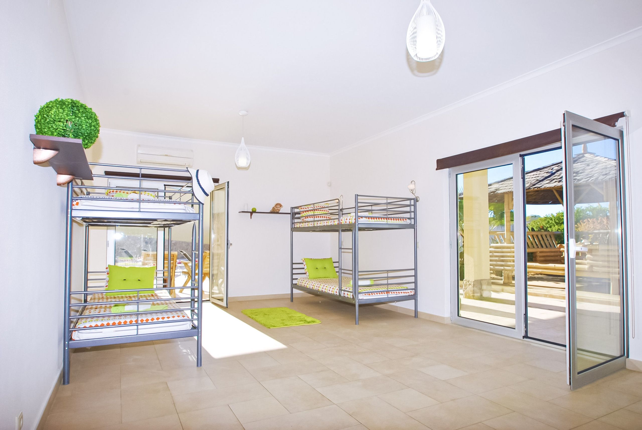 Une chambre avec des lits superposés, une petite plante et une porte-fenêtre coulissante donnant sur un espace extérieur.