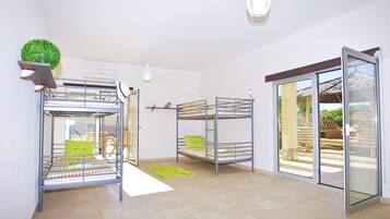 Une chambre avec des lits superposés, une petite plante et une porte-fenêtre coulissante donnant sur un espace extérieur.