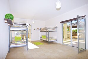Een kamer met stapelbedden, een kleine plant en een schuifdeur naar buiten.
