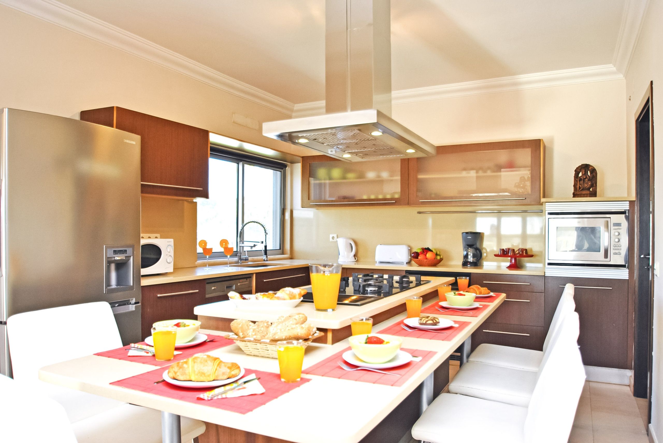 A modern kitchen with a dining area, equipped with a refrigerator, microwave, and stove.
