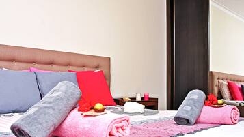 Una cama bien hecha con toallas enrolladas y almohadas decorativas, una mesita de noche con velas y un pequeño adorno.