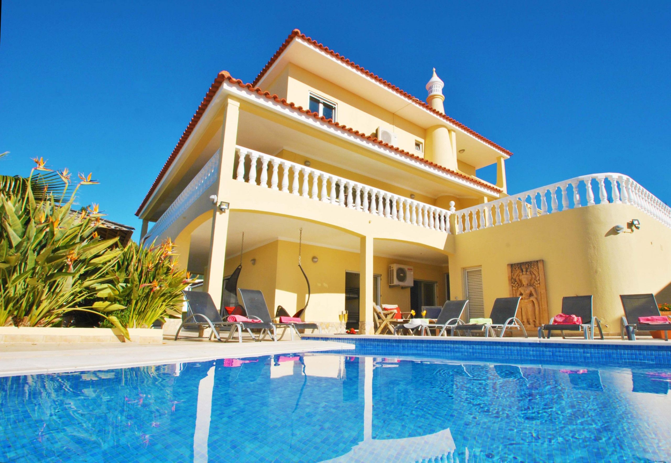 Un edificio de dos pisos con piscina, zona de estar exterior y balcón.