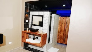 A modern bathroom with a wooden vanity, a black sink, and a mirror. - 1 Deluxe Lifestyle (Sosúa)