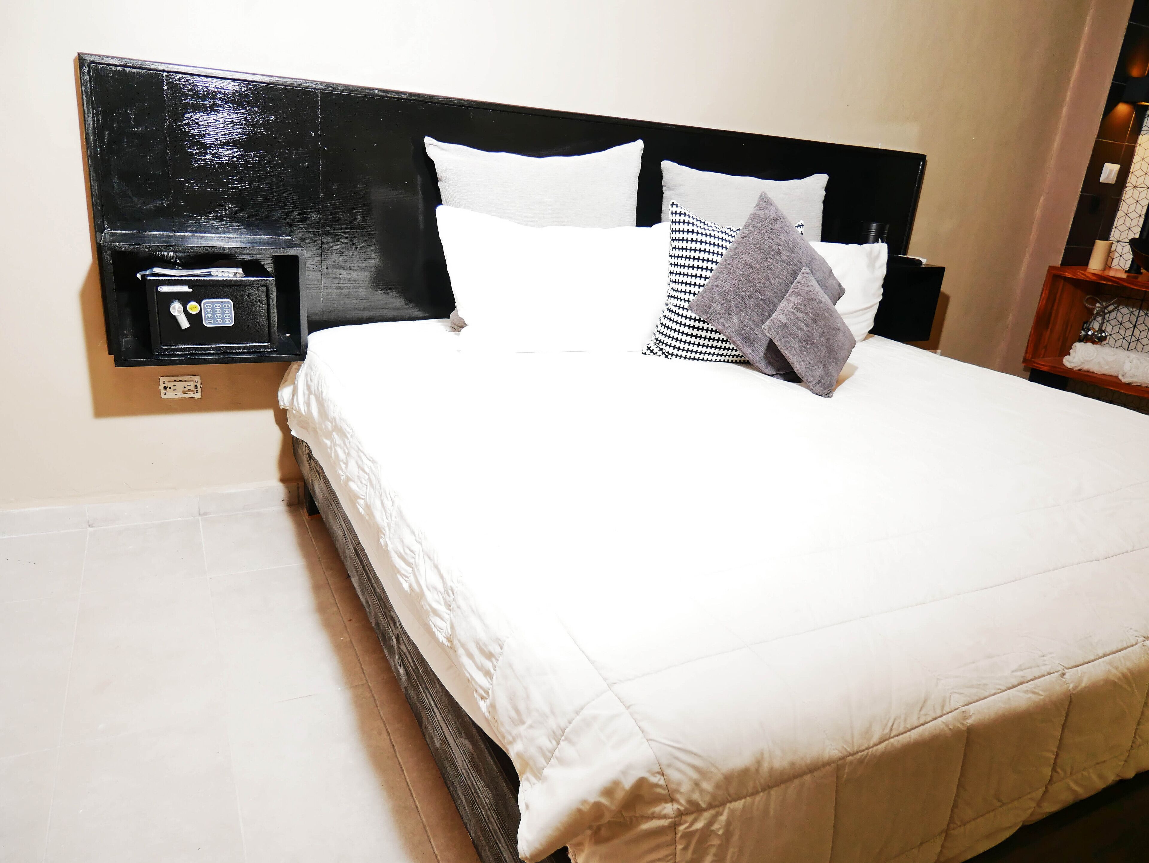 A neatly made bed with white bedding and a black headboard.