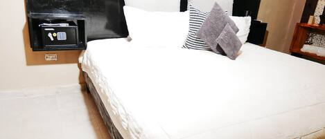 A neatly made bed with white bedding and a black headboard.