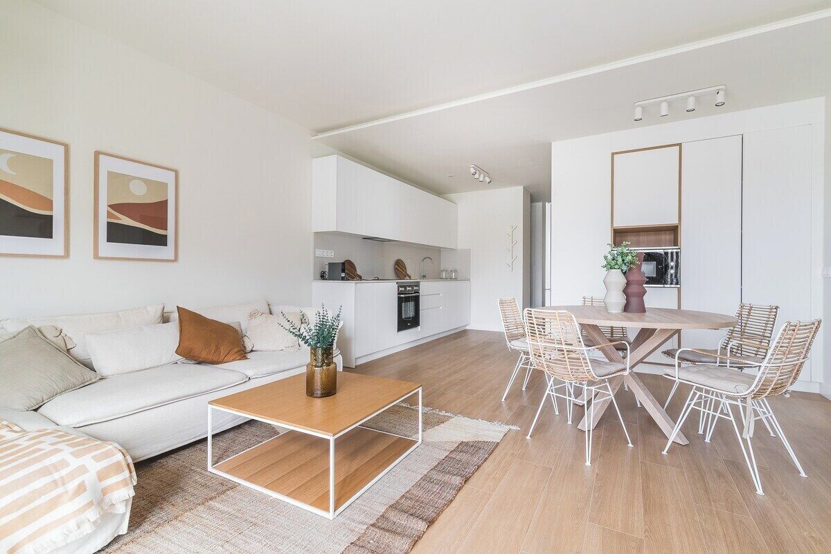 Un salon moderne comprenant un canapé, une table basse et un coin repas avec des chaises.