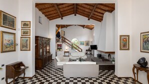 Un vaste espace de vie doté d’un sol à carreaux, d’un canapé blanc, d’un meuble en bois et d’un escalier menant à un niveau supérieur.