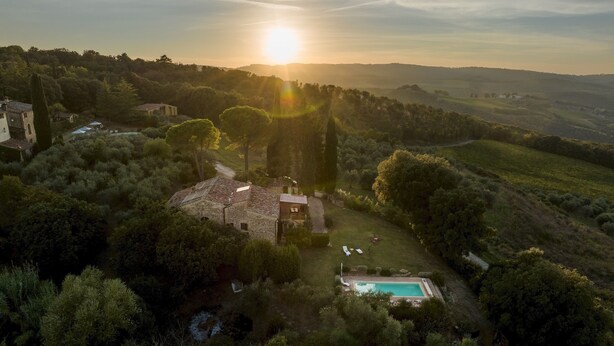 Une vue aérienne d’une villa entourée d’une végétation luxuriante, avec une piscine et un bâtiment en pierre.