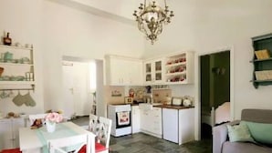 Un vaste espace de vie agrémenté d’un lustre, de meubles blancs, d’une table à manger avec des chaises et d’un canapé.