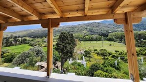 Une structure de pergola en bois offrant une vue sur un paysage verdoyant et luxuriant ainsi que sur des montagnes lointaines.