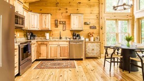 A wooden cabin-style kitchen with a central island, built-in appliances, and large windows. - Harper’s Hideaway- Close to Downtown Gatlinburg, Hot Tub, Guest Favorite! (Gatlinburg)