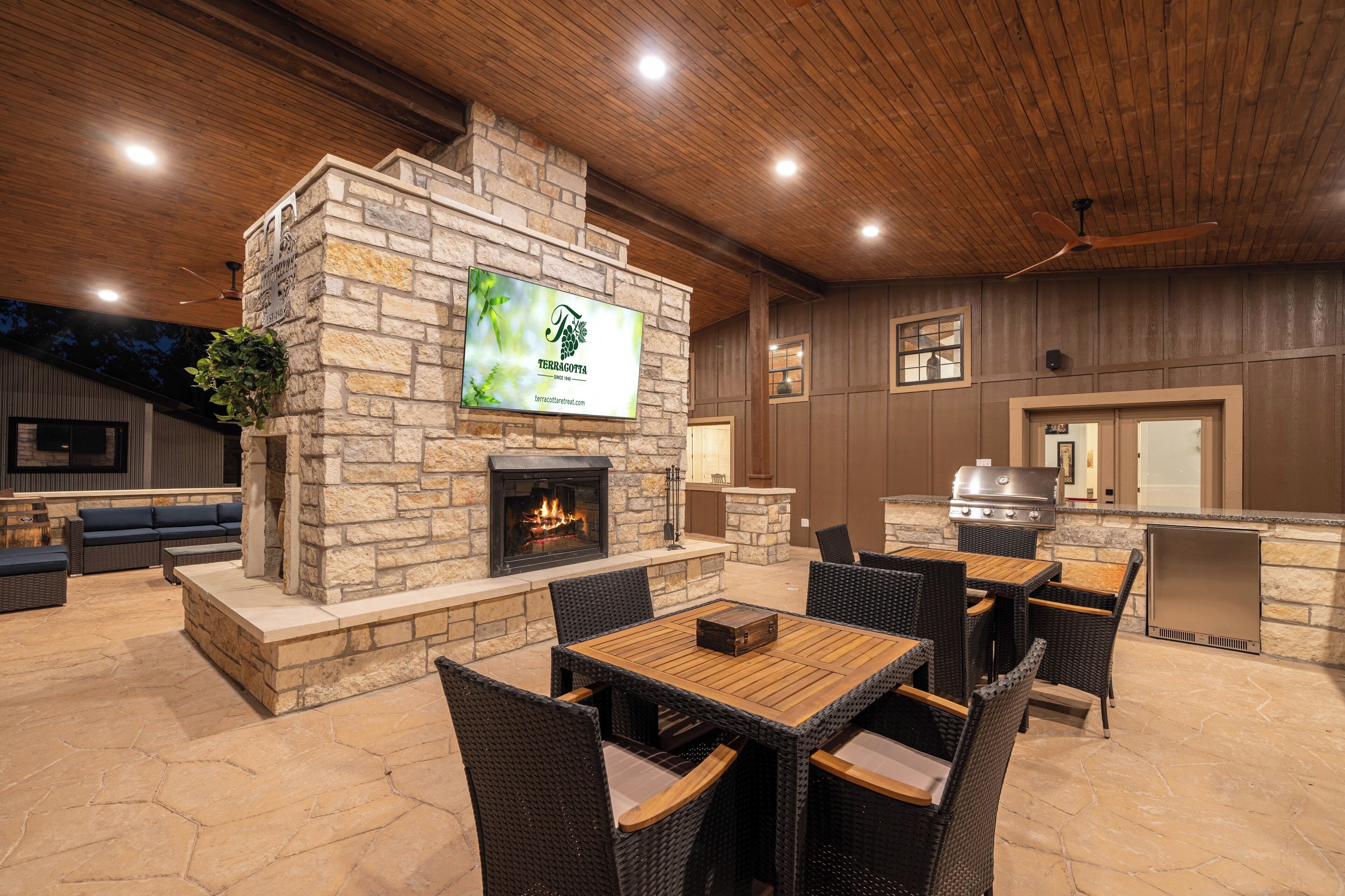 An outdoor patio with stone walls, a fireplace, and a grill area.