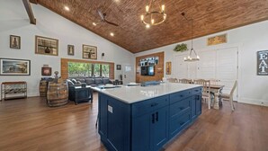A spacious kitchen with a large island, wooden ceiling, and modern appliances.