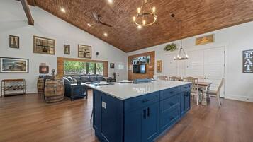 Een ruime keuken met een groot kookeiland, houten plafond en moderne apparatuur.