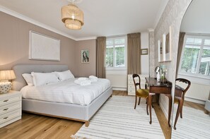 A bedroom with a bed, bedside table, lamp, and a desk with chairs. - Botanical bliss by UnderTheDoormat (London)