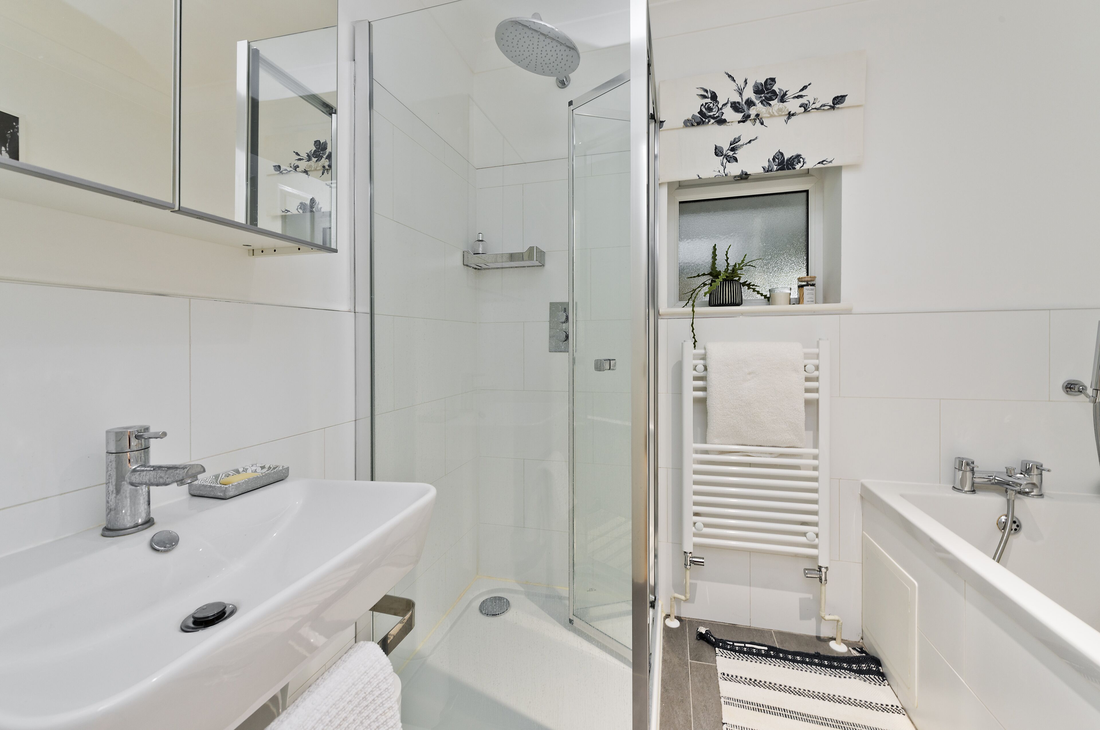 A modern bathroom with a glass-enclosed shower, a white sink, and a bathtub.