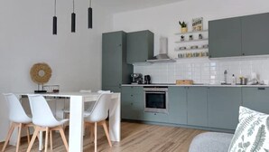 A modern kitchen with grey cabinets, a white countertop, and a dining area with white chairs. - Enrica apartment, elegant, near the lake historic center free parking (Lovere)