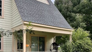 A house with a covered porch, a garden with various plants and flowers, and a brick pathway leading to the entrance.