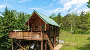A wooden cabin with a green roof, a deck, and a staircase. - Riverfront! Mountain views 4 Miles to Luray Caverns  hot tub! at Line cabin (Luray)