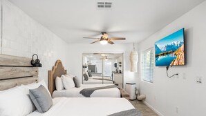 A modern bedroom with two beds, a ceiling fan, a TV, and a large window. - 5 min to Old Town-Sleeps 12-Heated Pool-King Bed-Ping Pong-Fire Pit (Scottsdale)